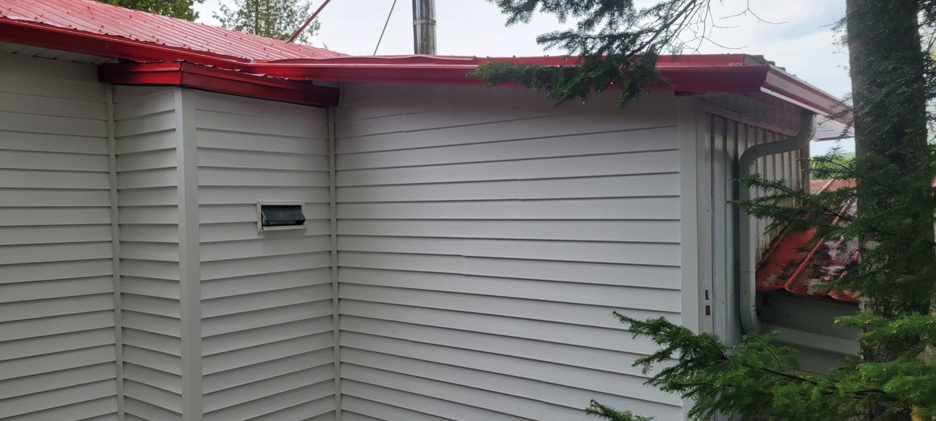 Une maison blanche avec un toit rouge est entourée d'arbres.