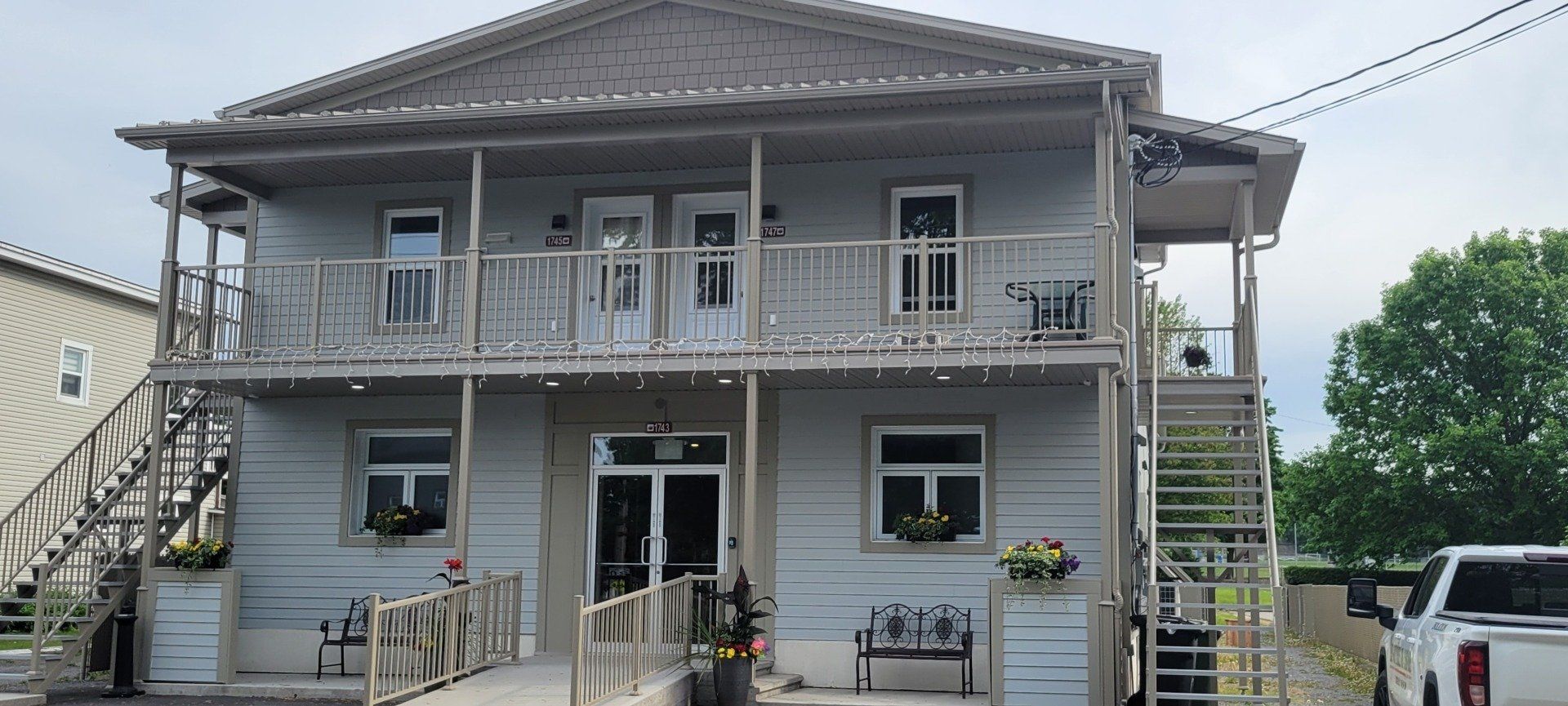 Une grande maison blanche avec des escaliers et un camion garé devant.
