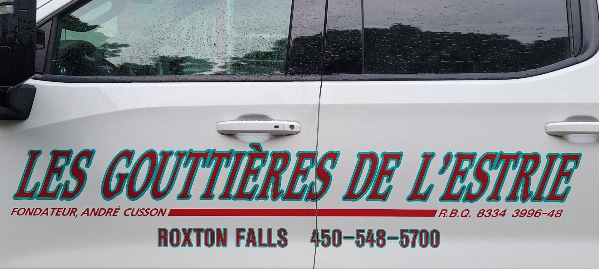 Un camion blanc avec les mots les gouttières de l'Estrie sur le côté