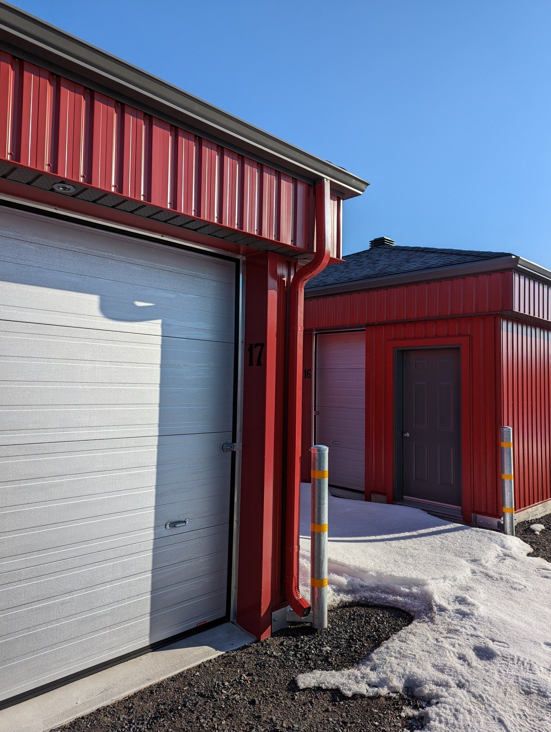 Un bâtiment rouge avec une porte de garage blanche est à côté d'un bâtiment rouge avec une porte de garage blanche.