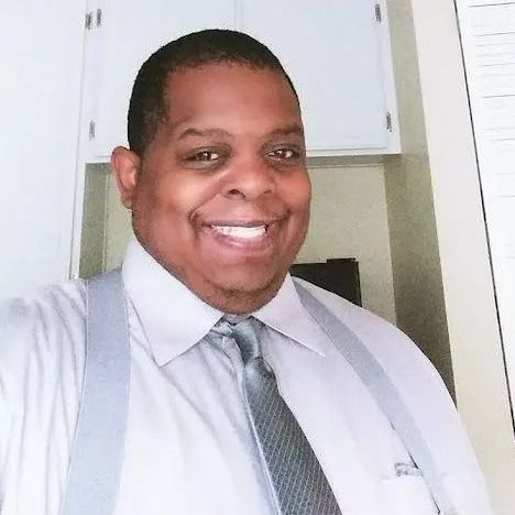 A man in a white shirt and tie is smiling for the camera.