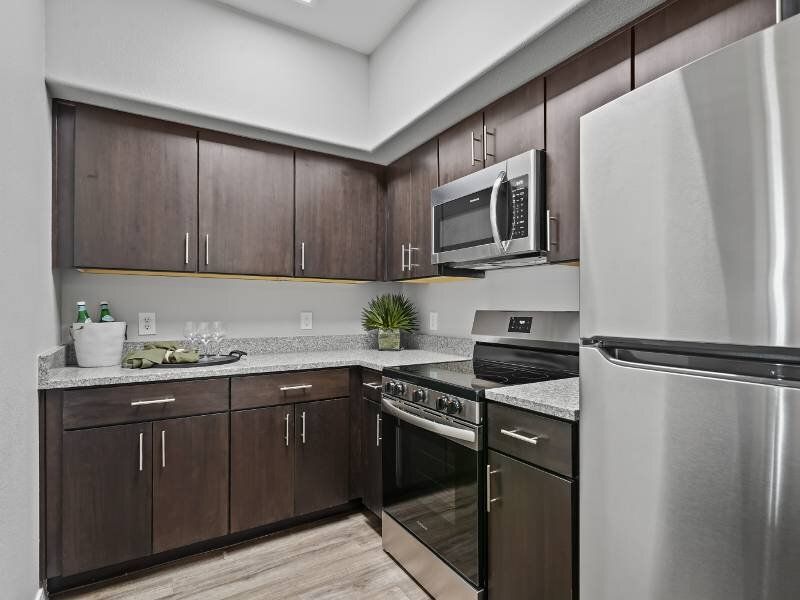 L-shaped kitchen with dark wood cabinets, granite countertops, and stainless steel appliances.