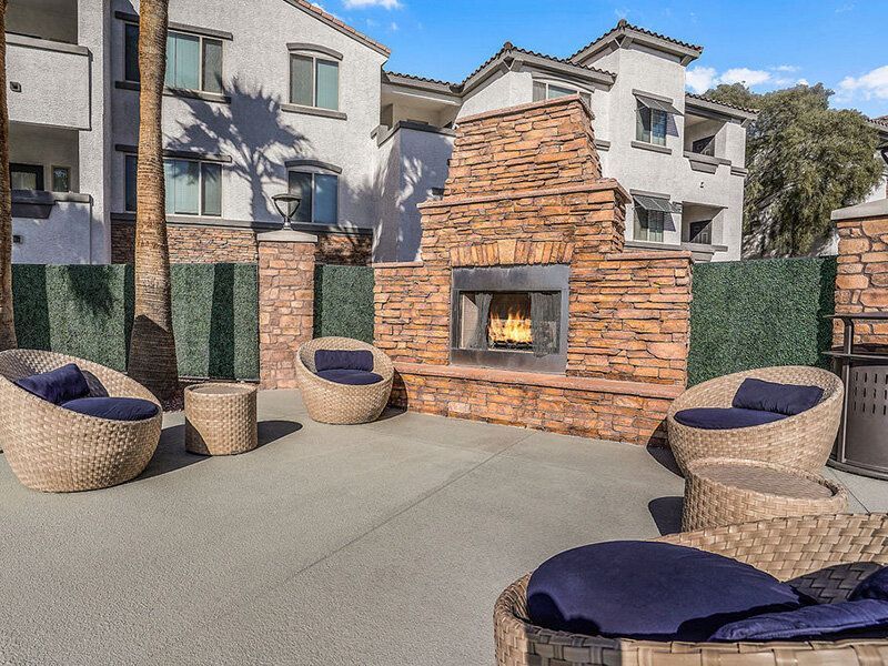 Outdoor communal lounge with a stone fireplace and circular wicker seating.