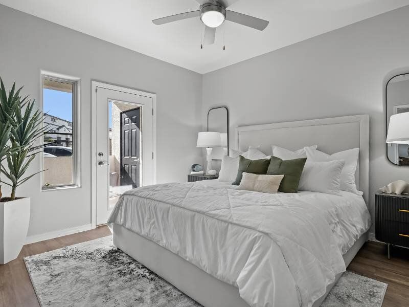 Bright modern bedroom with a white bed, two nightstands, a ceiling fan, and a patio door.