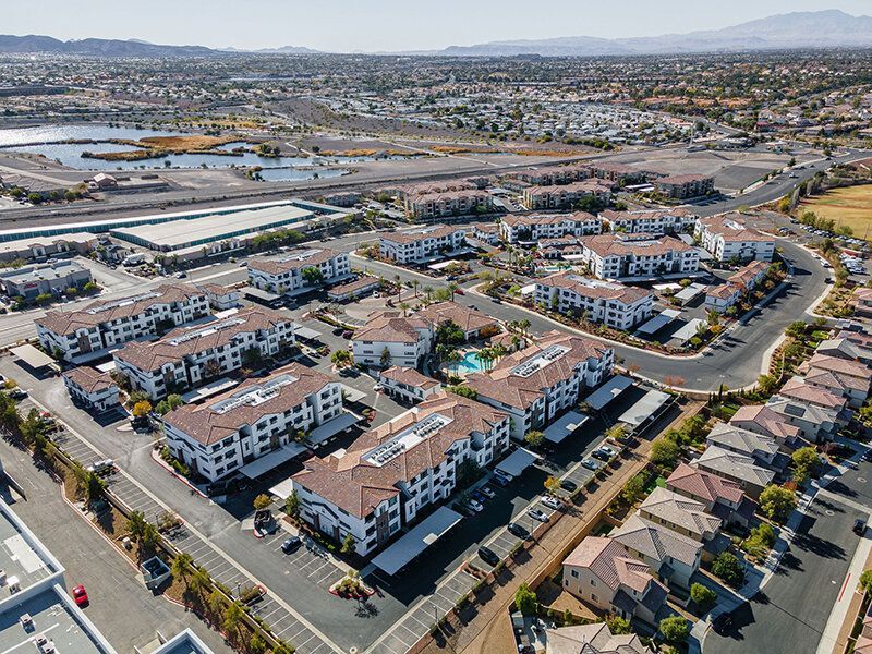 Aerial view of a large multifamily apartment community with multiple buildings, roads, and a central pool.