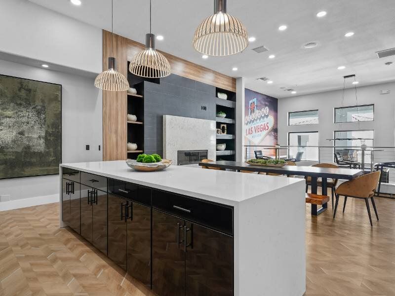 Modern communal kitchen with white island, pendant lights, and a seating area.