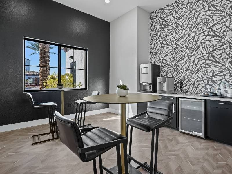 Modern apartment kitchen with round table, black accent wall, and stainless-steel appliances.