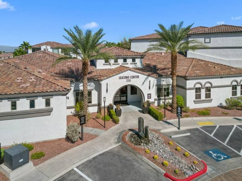 Exterior view of a leasing center with archway, palm trees, and parking.