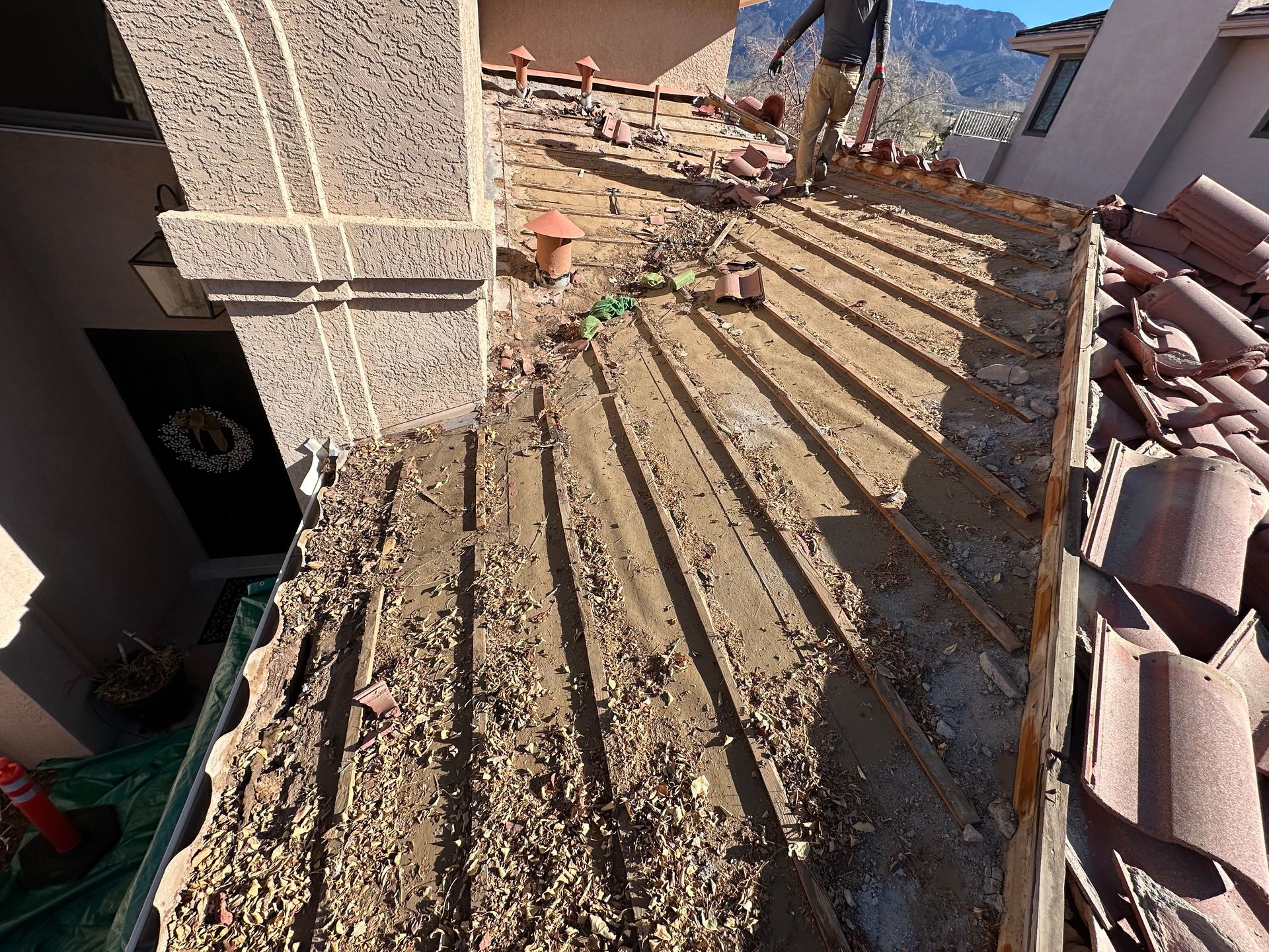 Aerial view of a house roof under construction, blue tarp covering sections.
