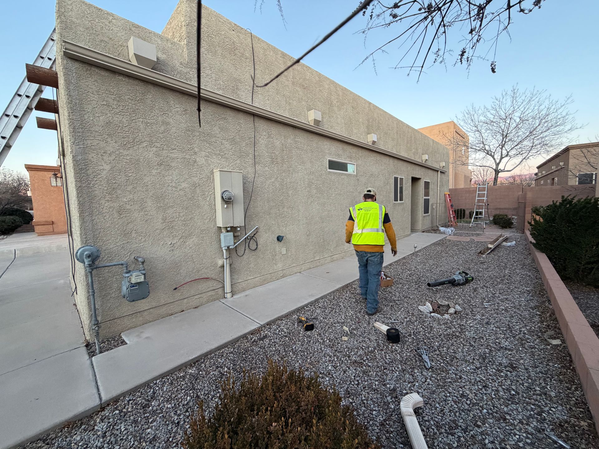 Tan metal roof with skylights and chimney against a cloudy sky, seen from a high angle.