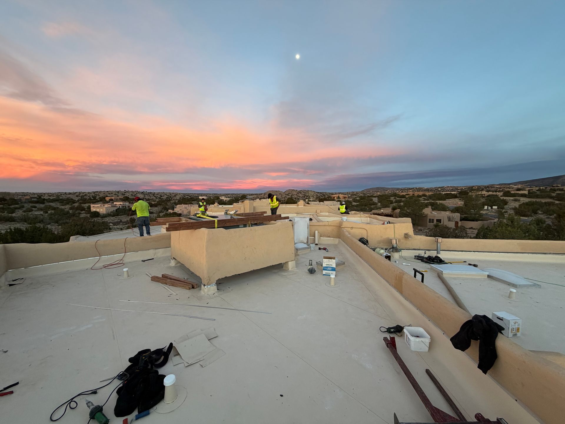 Aerial view of a commercial building with a white flat roof and mechanical equipment. Red umbrellas are visible on the left.