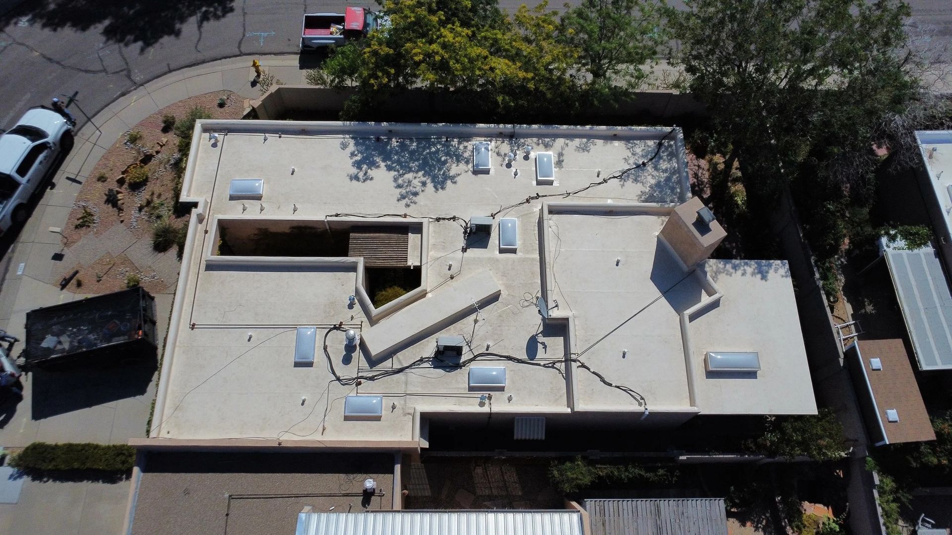 Person taking a photo of a flat roof with various vents, in a city.