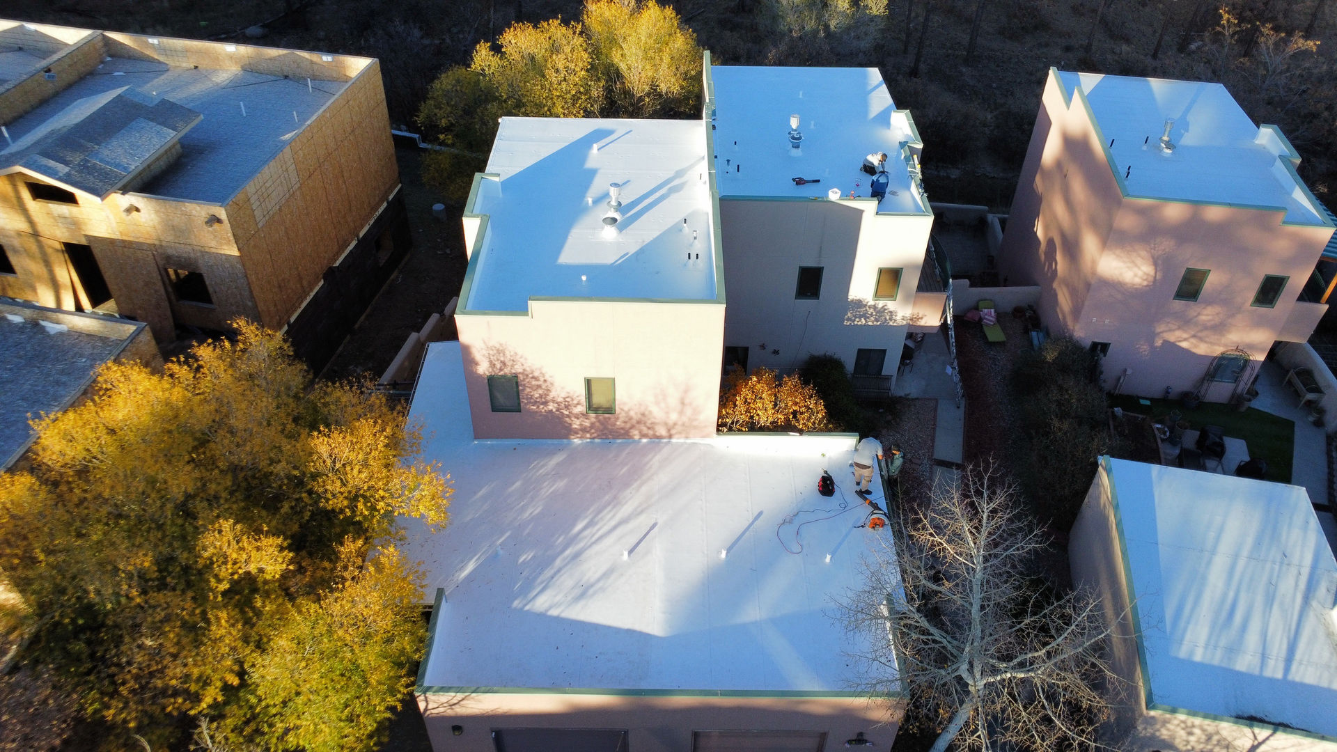 Overhead view of a flat, white roof with tools, against a cloudy sky and distant landscape.