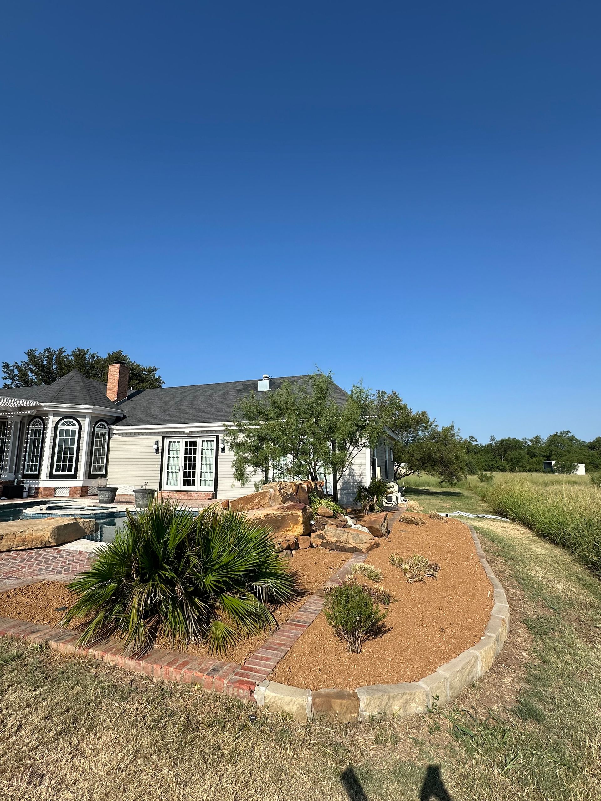 A white house with a landscaped yard under a clear blue sky.