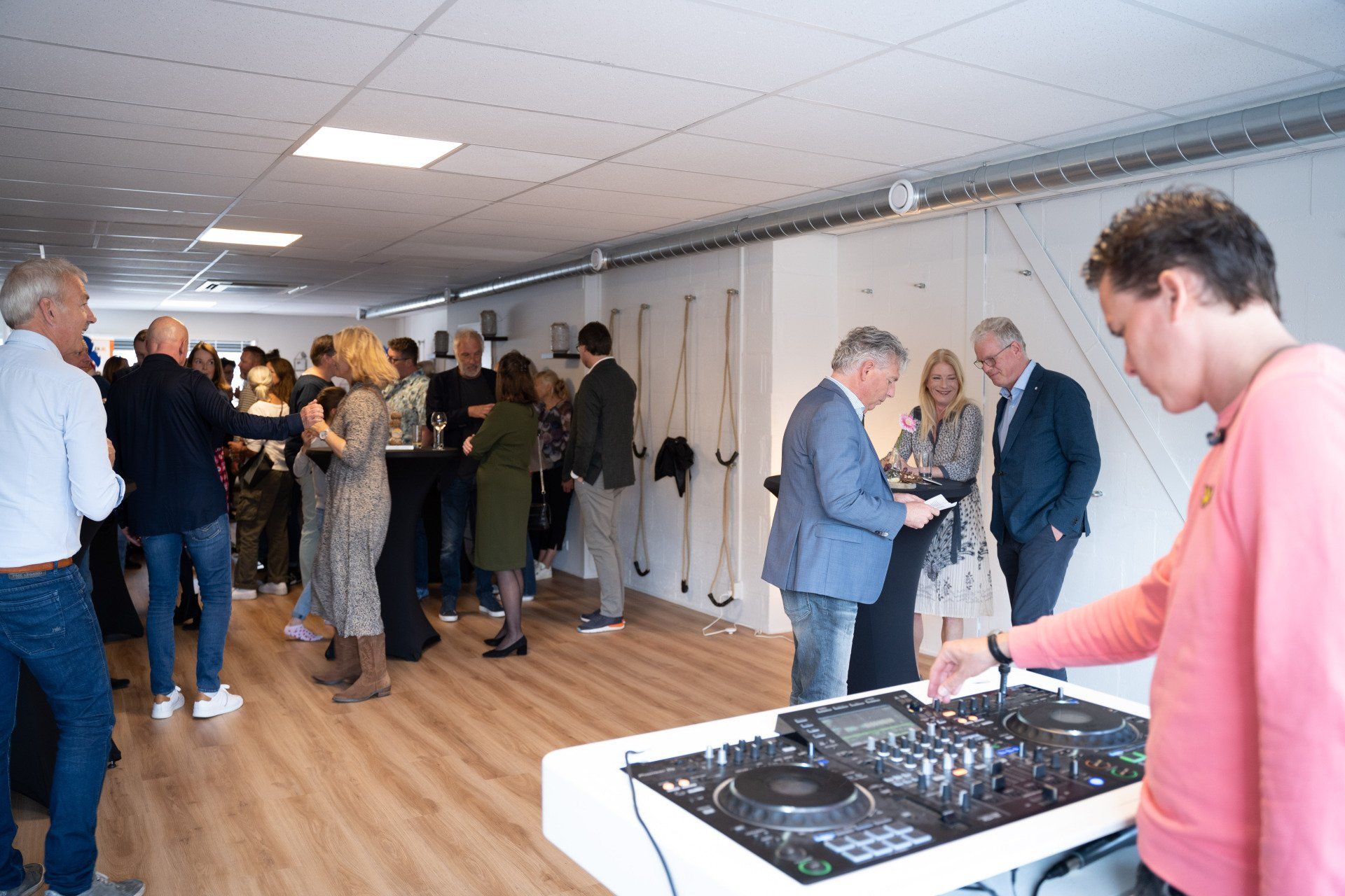 Een groep mensen staat rond een dj-booth in een kamer.