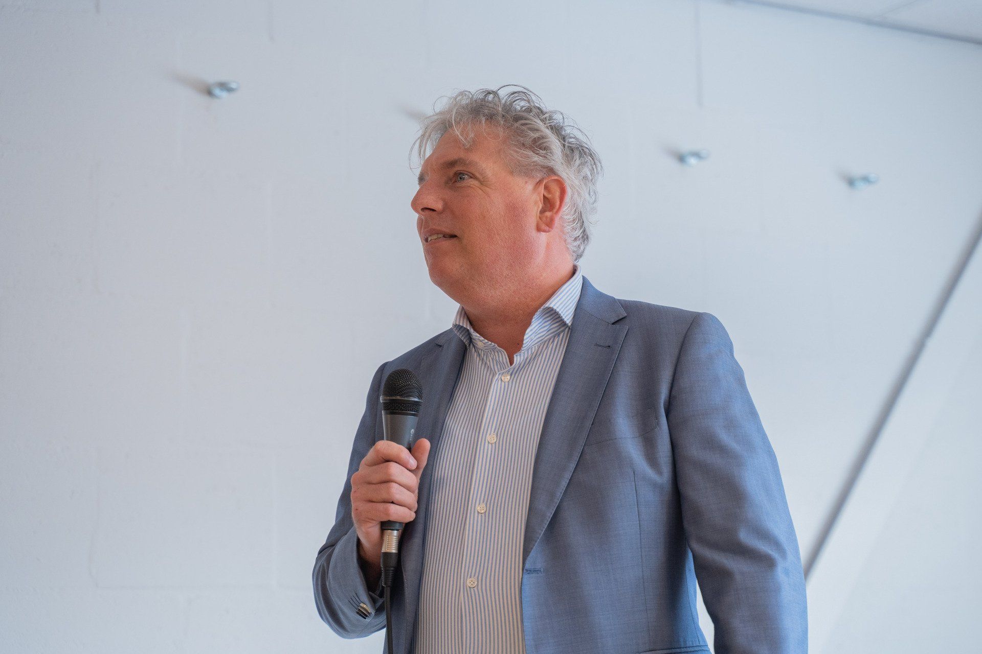 Een man in pak houdt een microfoon in zijn hand.