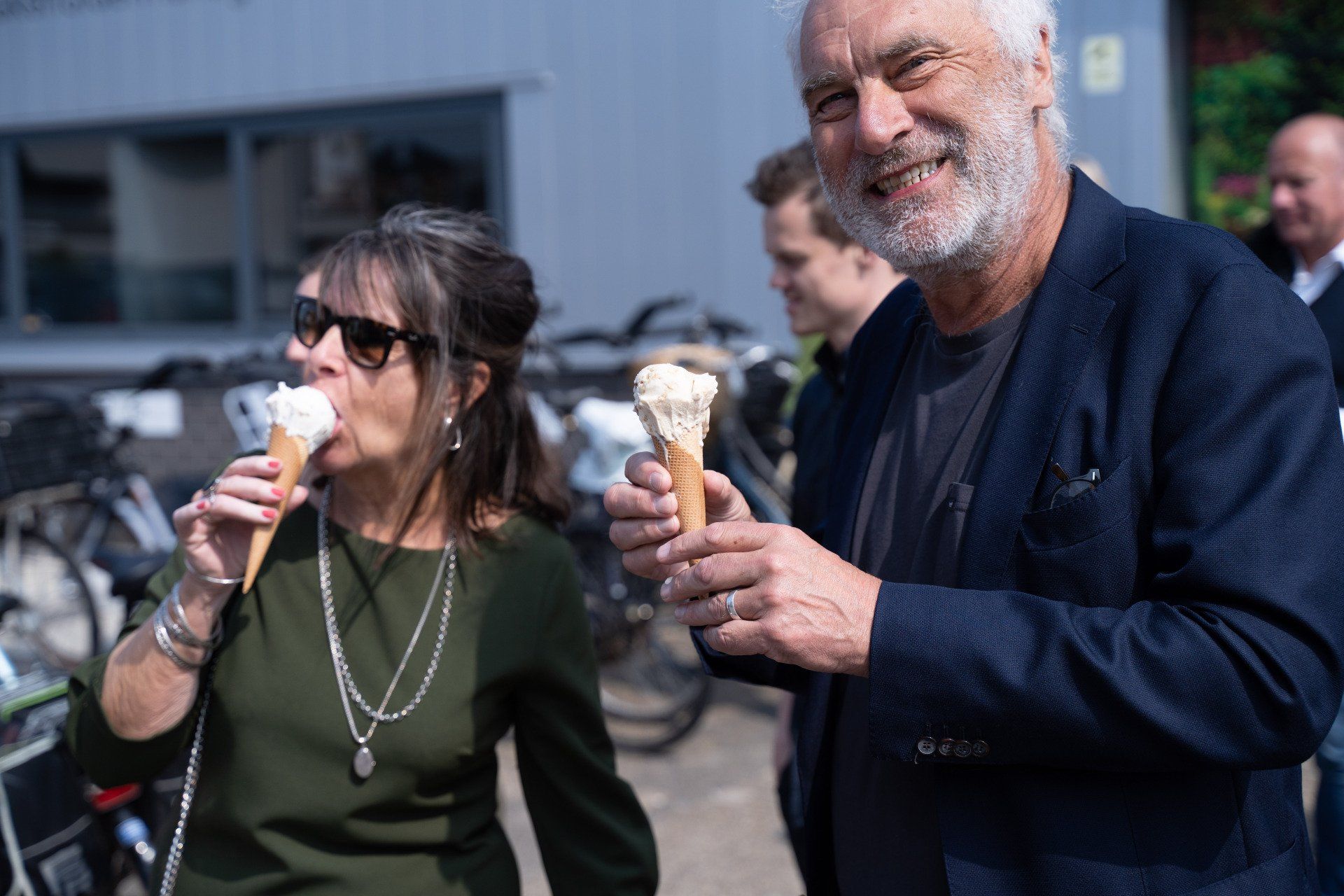 Een man en een vrouw eten ijs voor een gebouw.