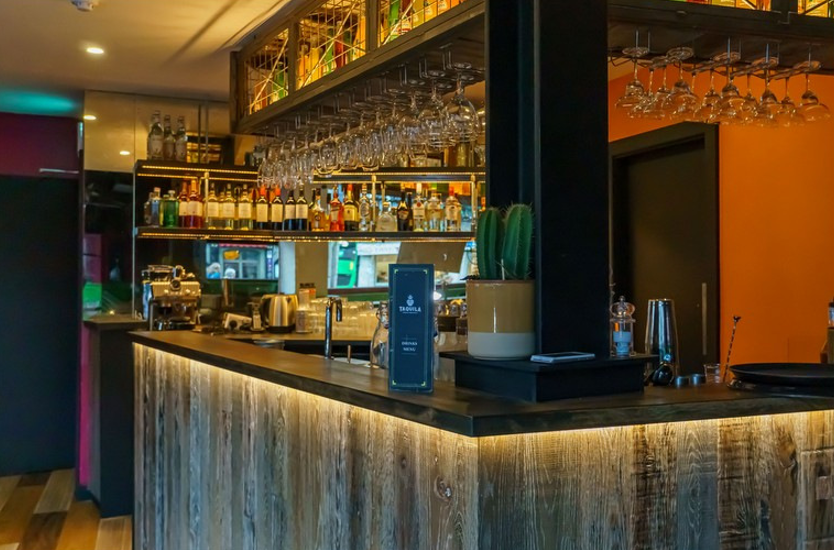 A bar in a restaurant with a menu on the counter