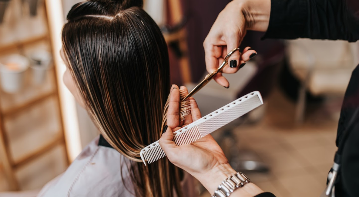 A woman is getting her hair cut by a hairdresser in a salon.
