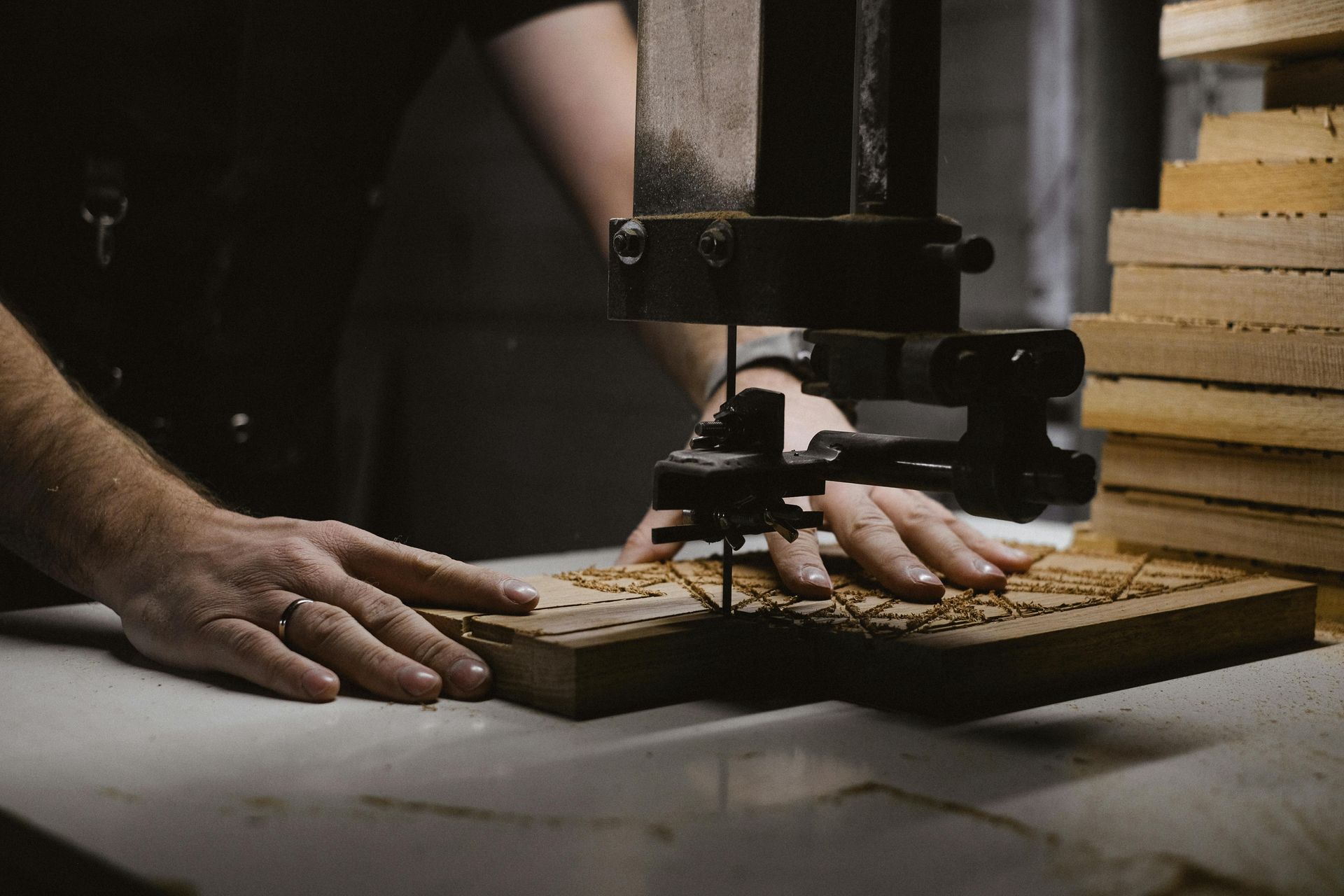 A man is using a band saw to cut a piece of wood.