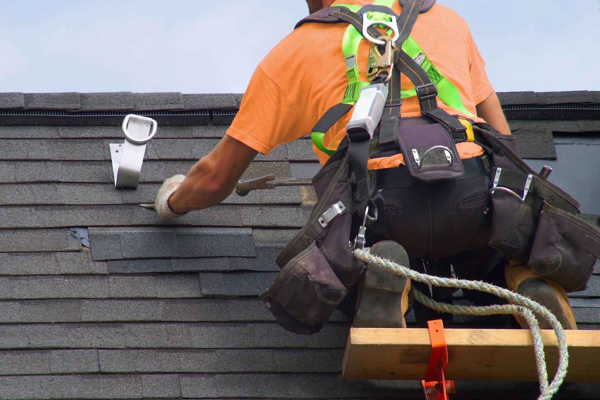 A man wearing a harness is working on a roof.