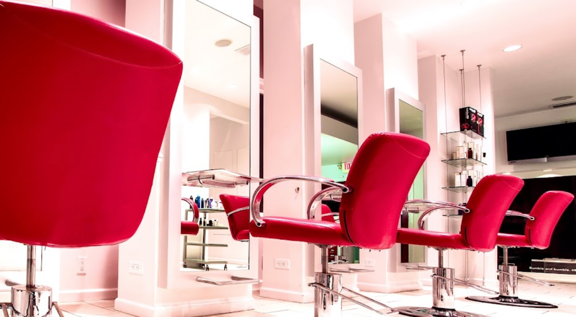 A hair salon with red chairs and mirrors
