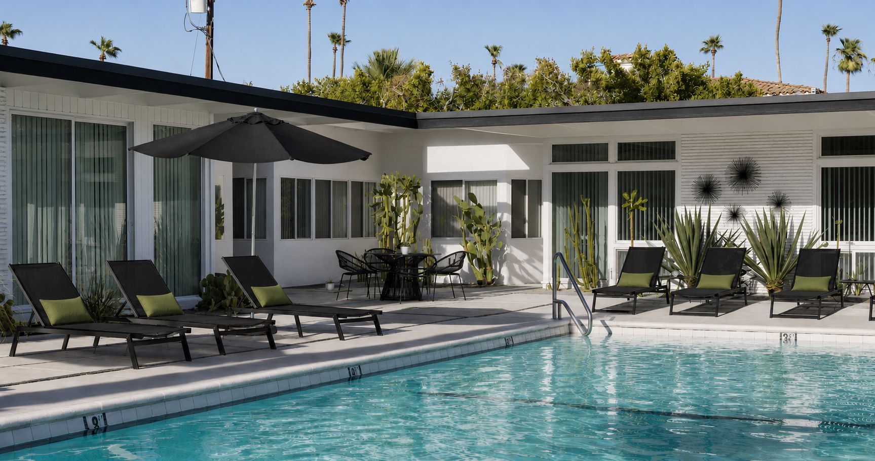 Modern courtyard with a swimming pool, lounge chairs, and a white mid-century style house.