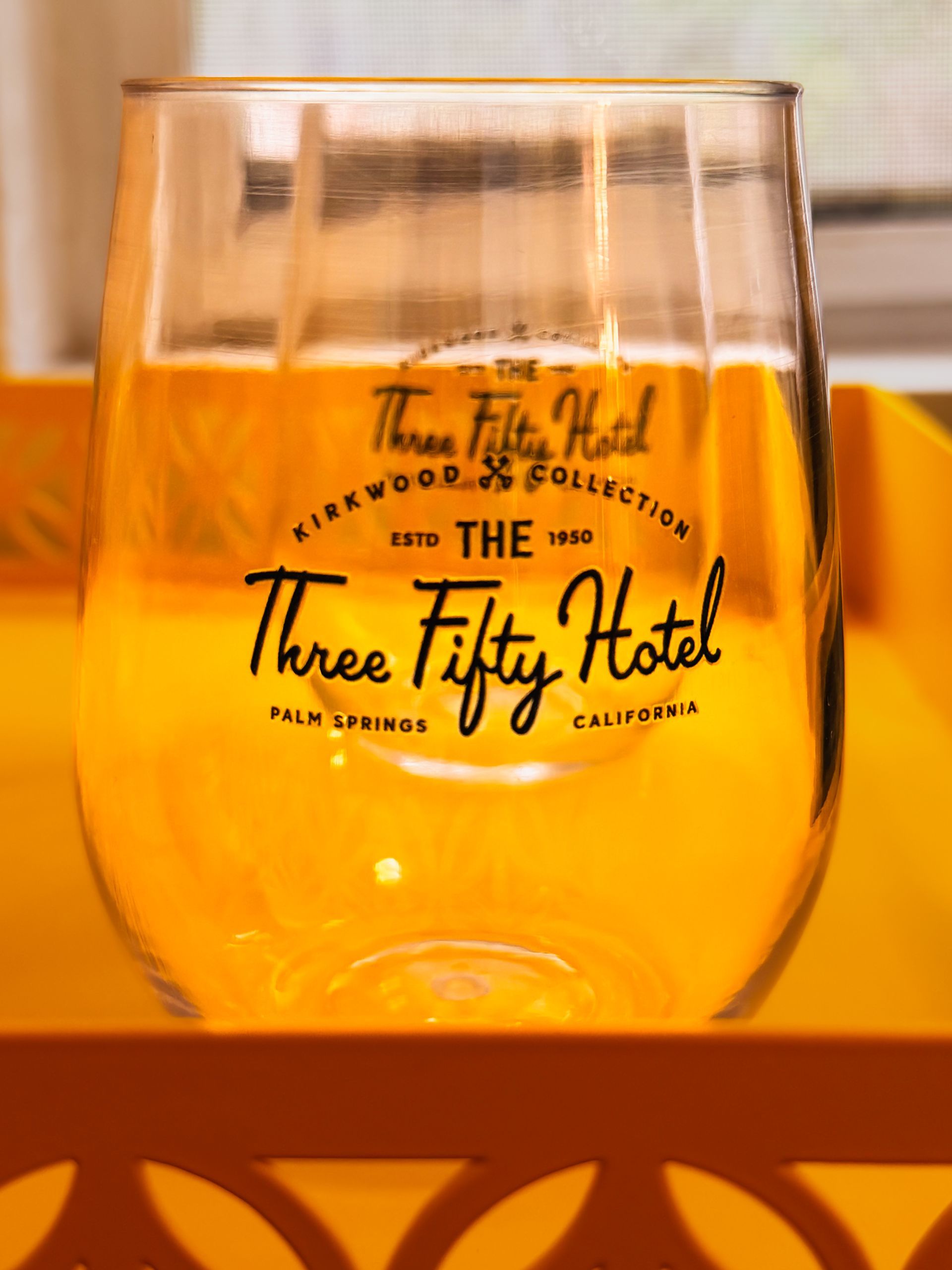 Clear pint glass with The Three Fifty Hotel logo on an orange background