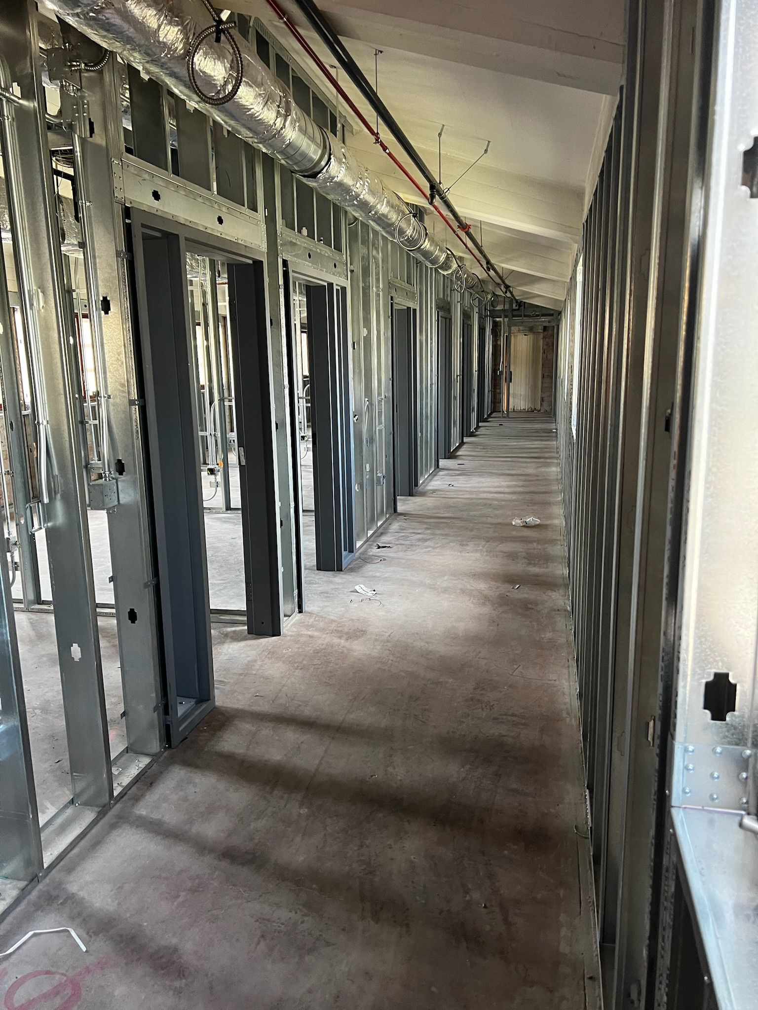 Interior view of a hallway under construction, metal framing and door frames visible.