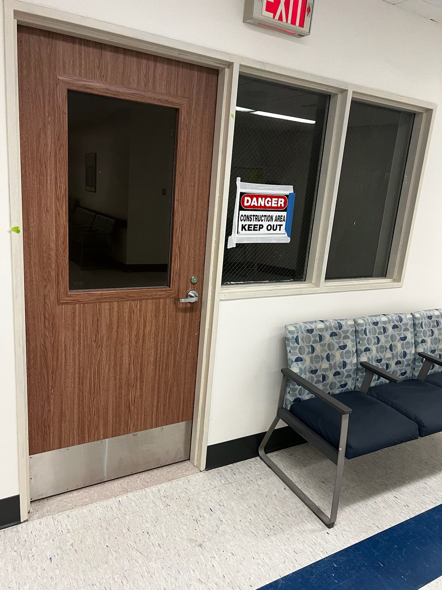 Door with a window, exit sign above. A sign in the window reads 