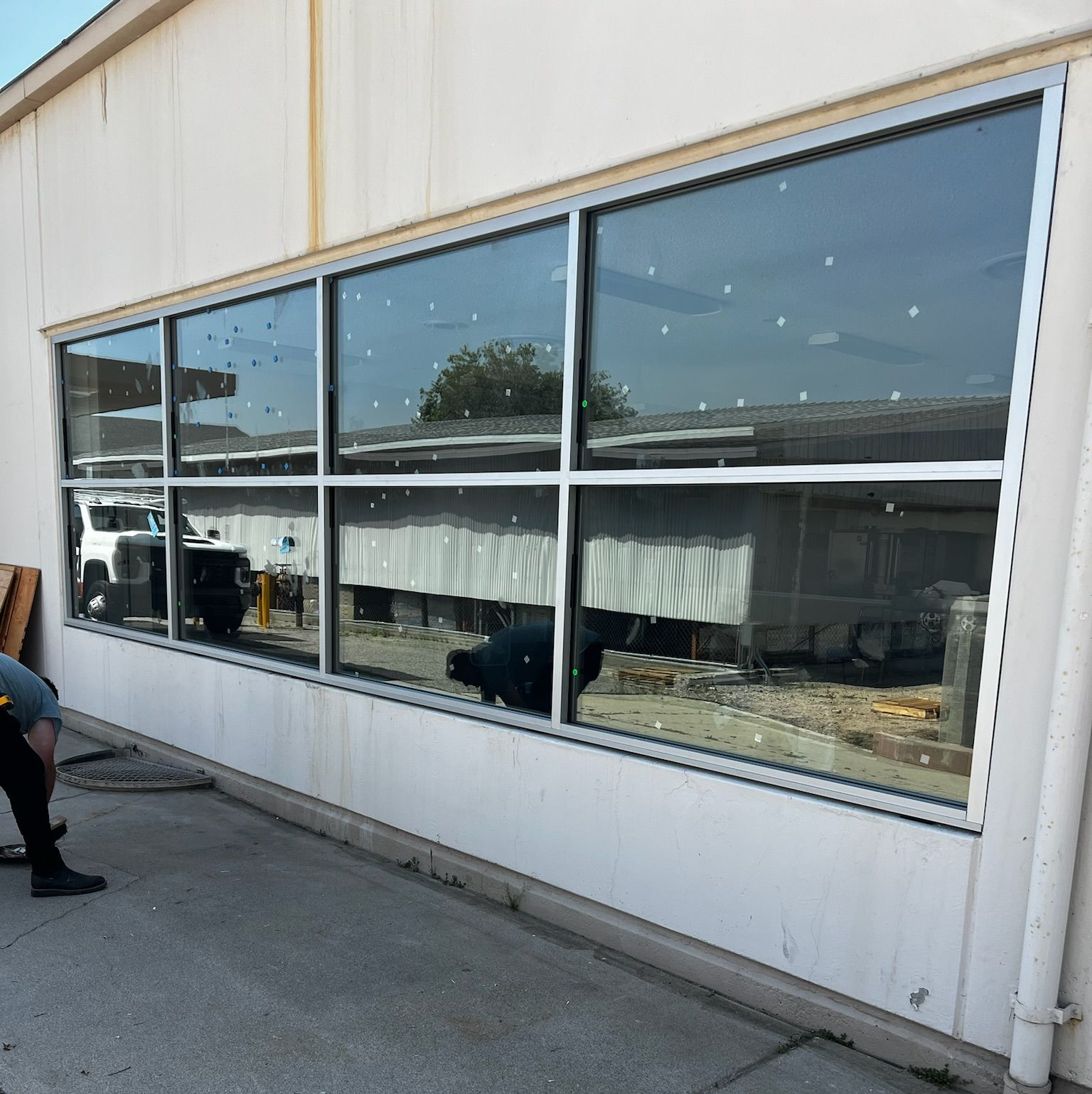 Large windows in a white building reflect outdoor scene. Person standing near the building.