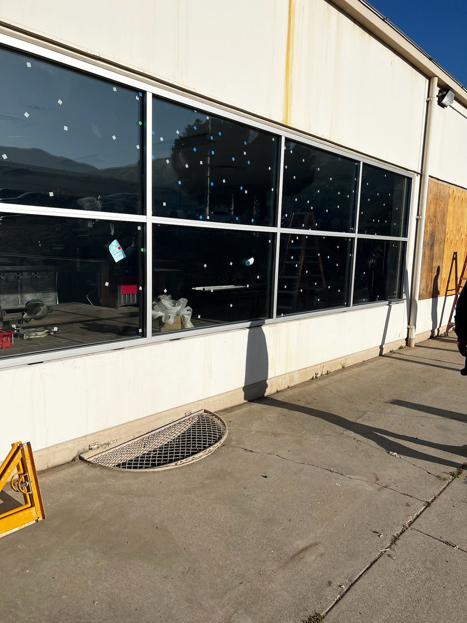Exterior of a building with large windows. Snowshoes and a construction sign sit on a concrete surface.