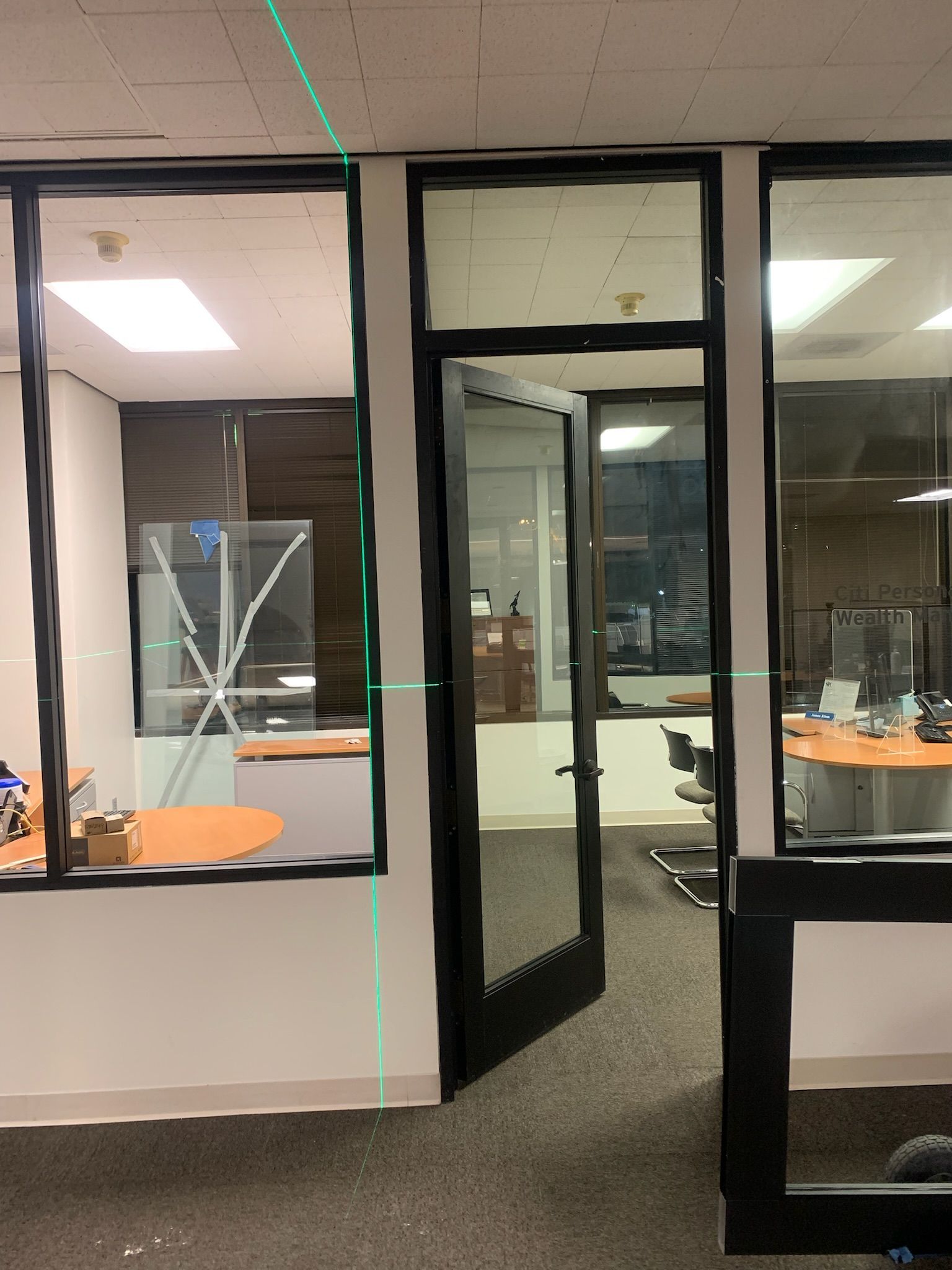 Interior office space with glass walls, door, and green laser level.
