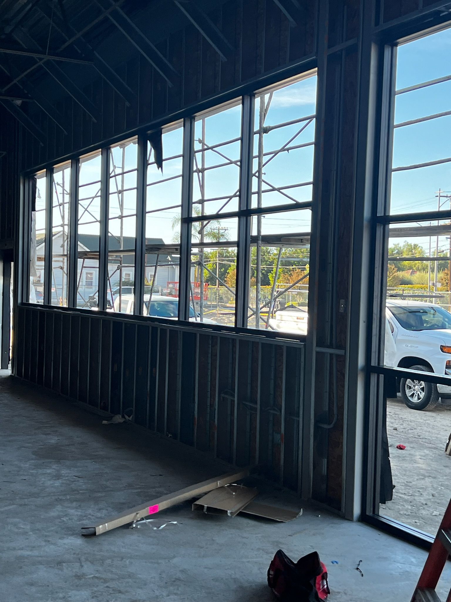 Interior view of a building under construction, featuring large windows and exposed metal framing.