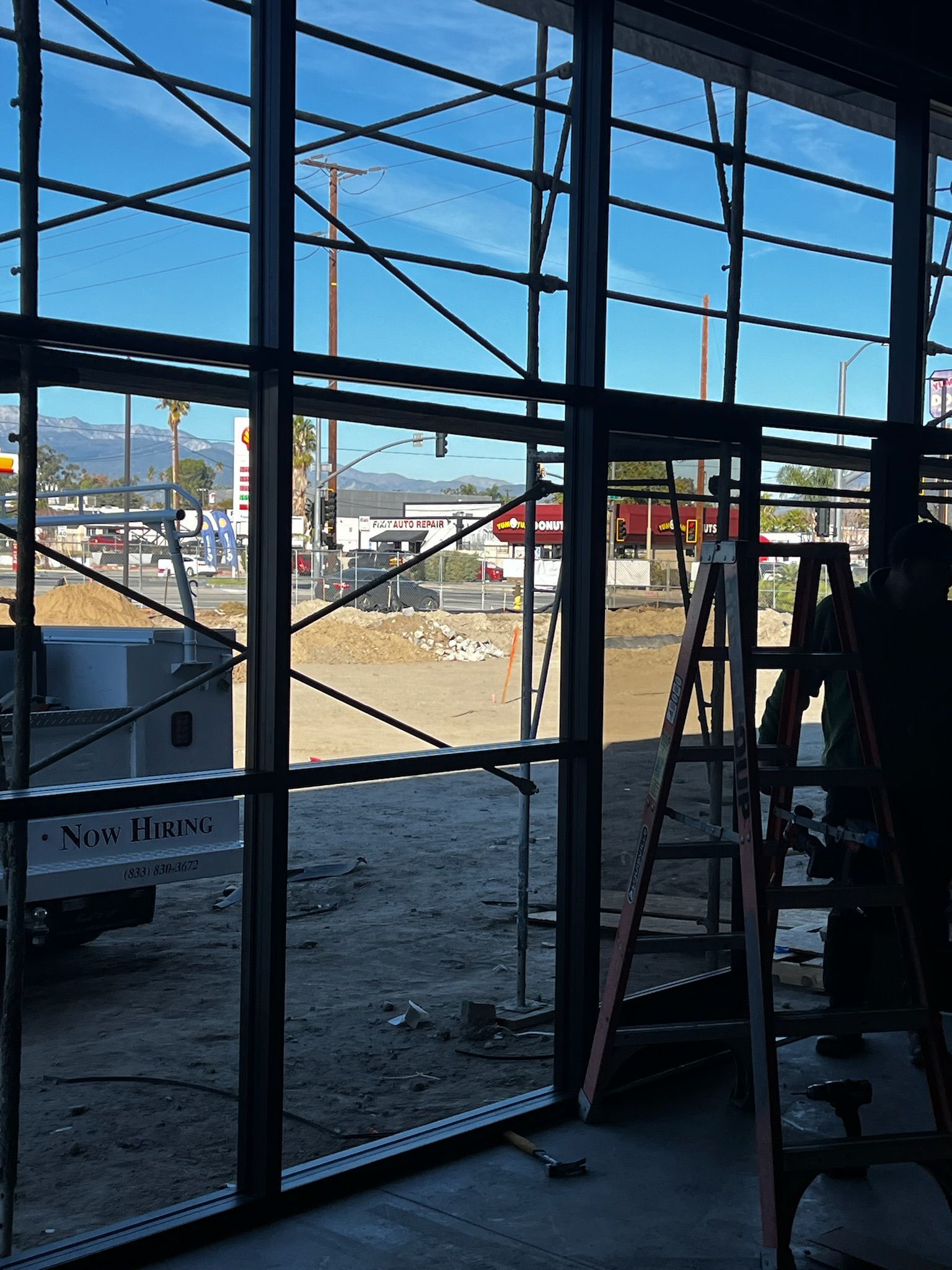 Interior view of a building under construction, looking out at a street scene; ladder present.