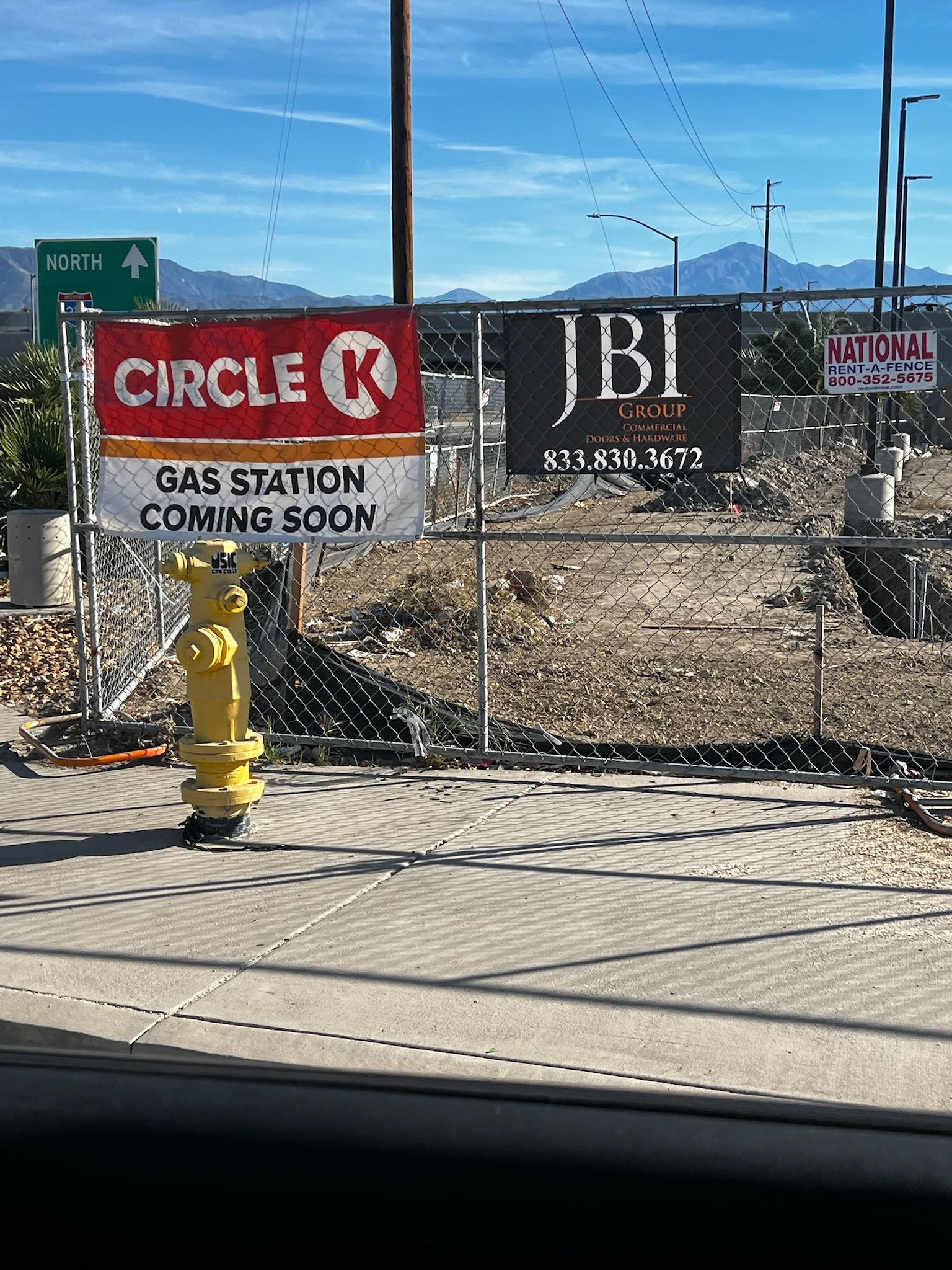Construction site with Circle K and JBI signs, gas station coming soon. Mountains in the background.