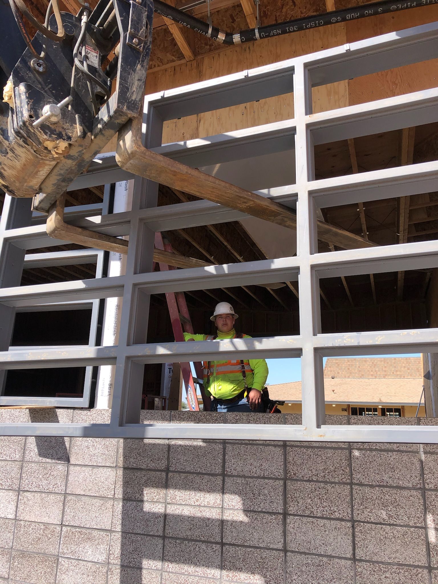 Construction worker in safety vest inside a building frame, operating machinery.