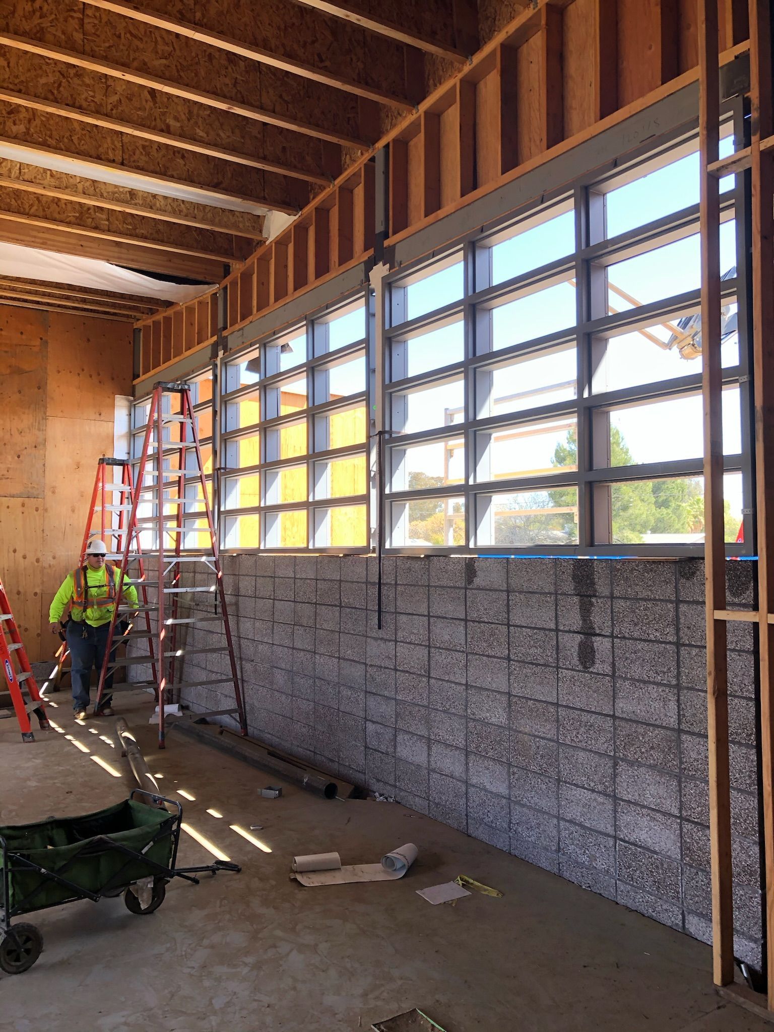 Construction site interior with worker, windows, and partially built walls.