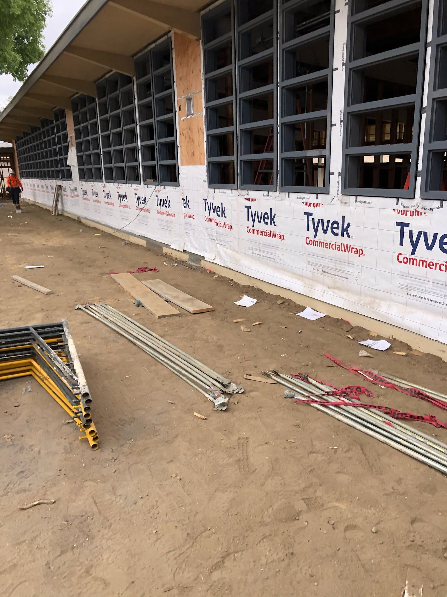 Construction site: building exterior with windows, scaffolding, and materials on the ground.