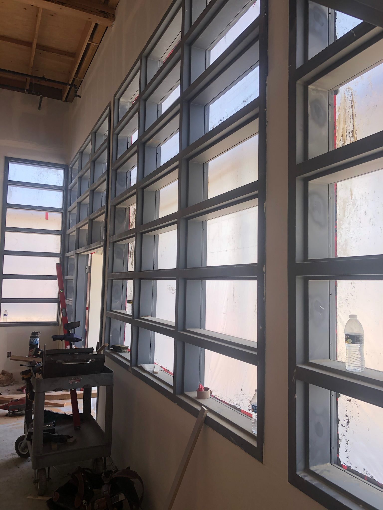 Metal frame windows in a building under construction, with a cloudy sky visible through the panes.