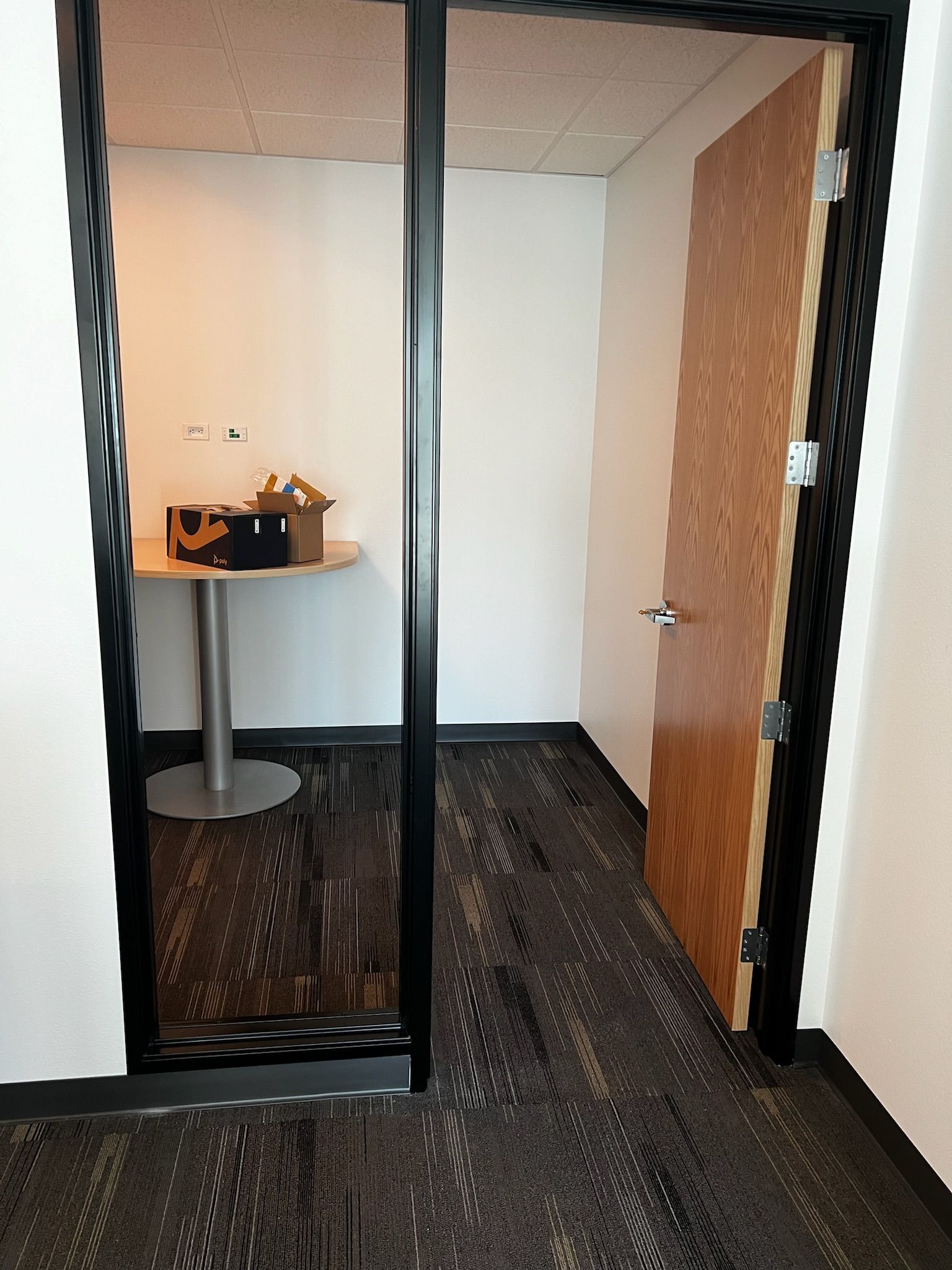 Office space with open doorway revealing a small room with a table, and a closed door.