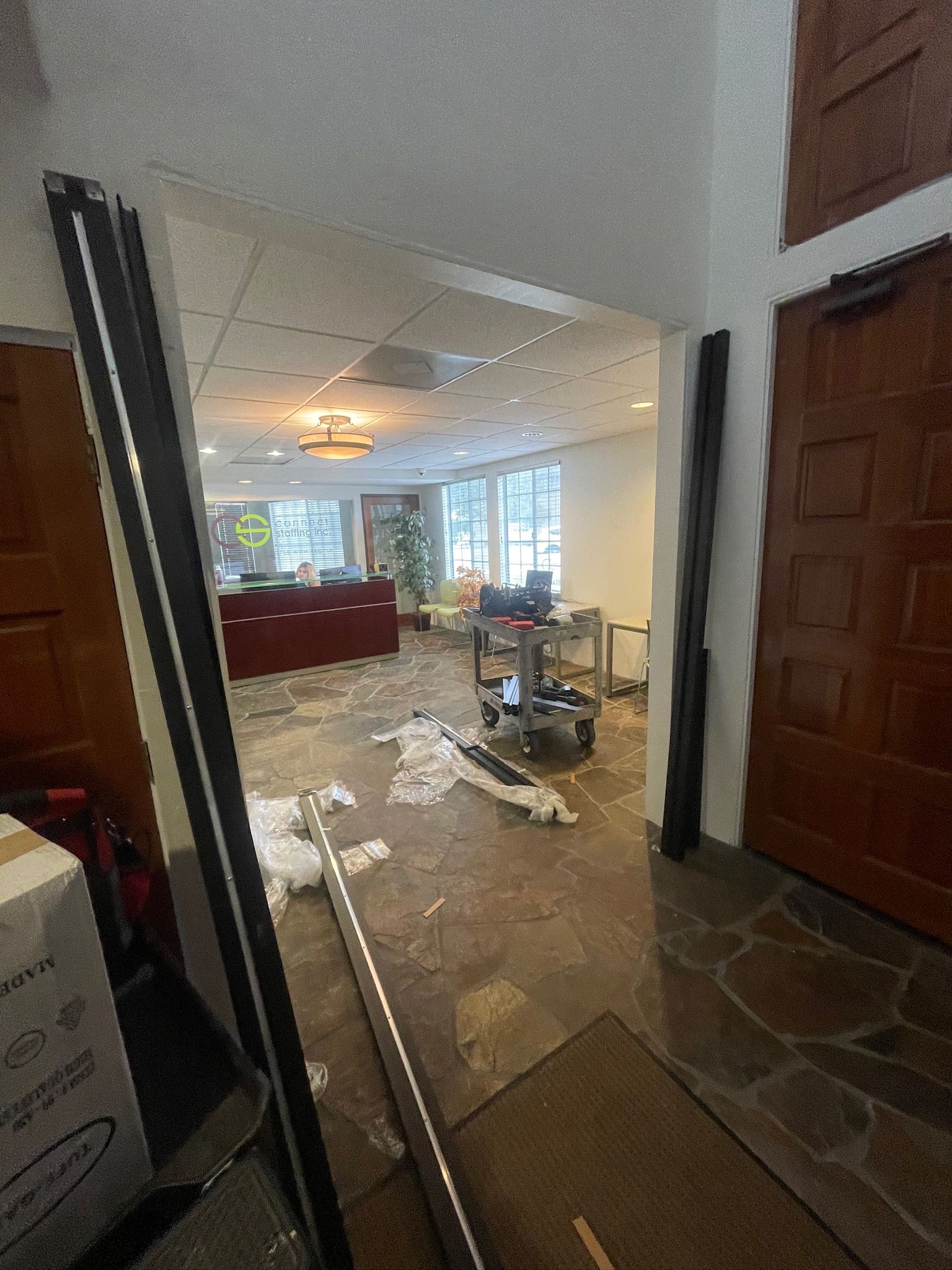 Hallway with open doorway to a room under construction. Debris on the floor, red cabinets, and light fixtures visible.