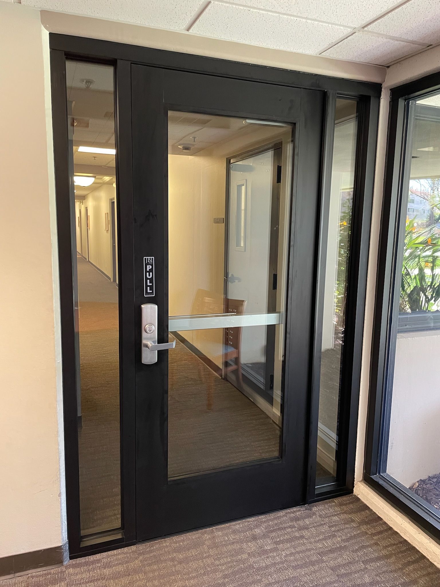 Black door with glass panel, hallway visible. 