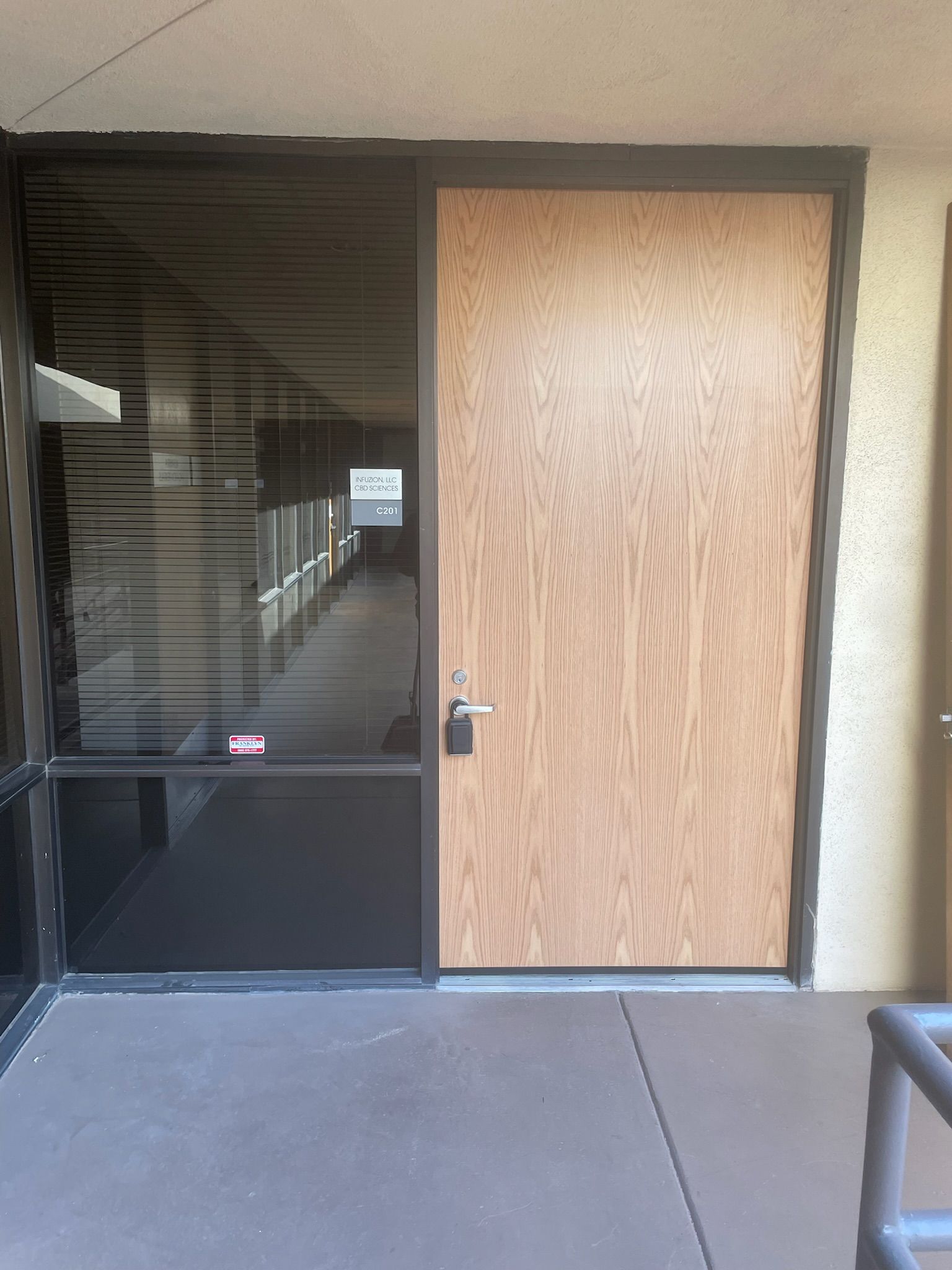 Door with a window and hallway. The door is wooden with a silver door handle.