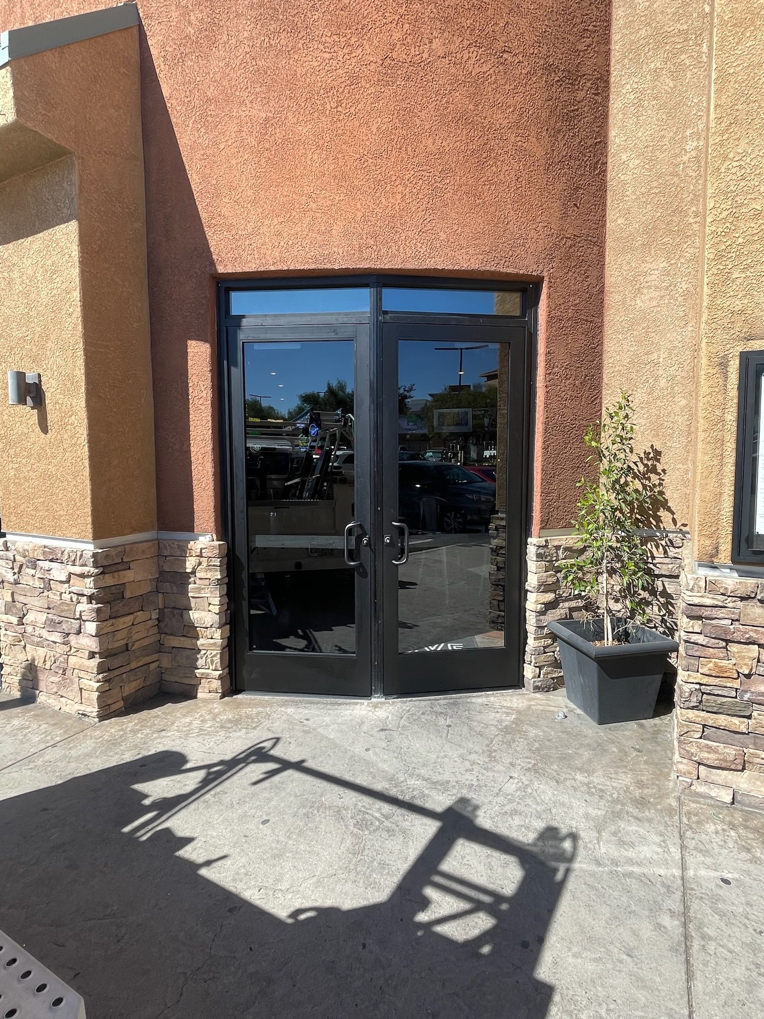 Black double doors with reflective glass, flanked by stone columns, lead into a building.