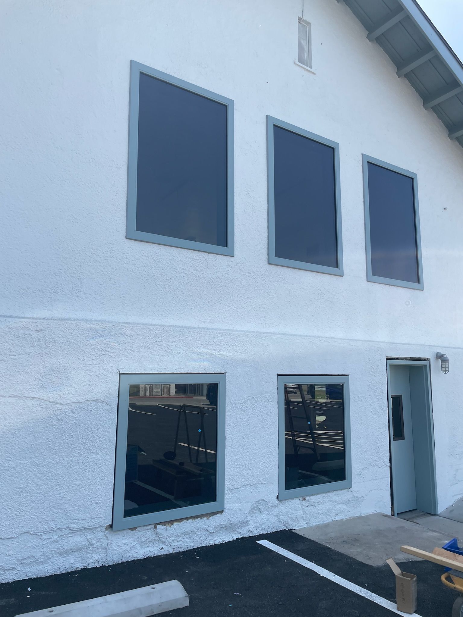 Door with window and sign, next to windows and a bench. Exit sign above.