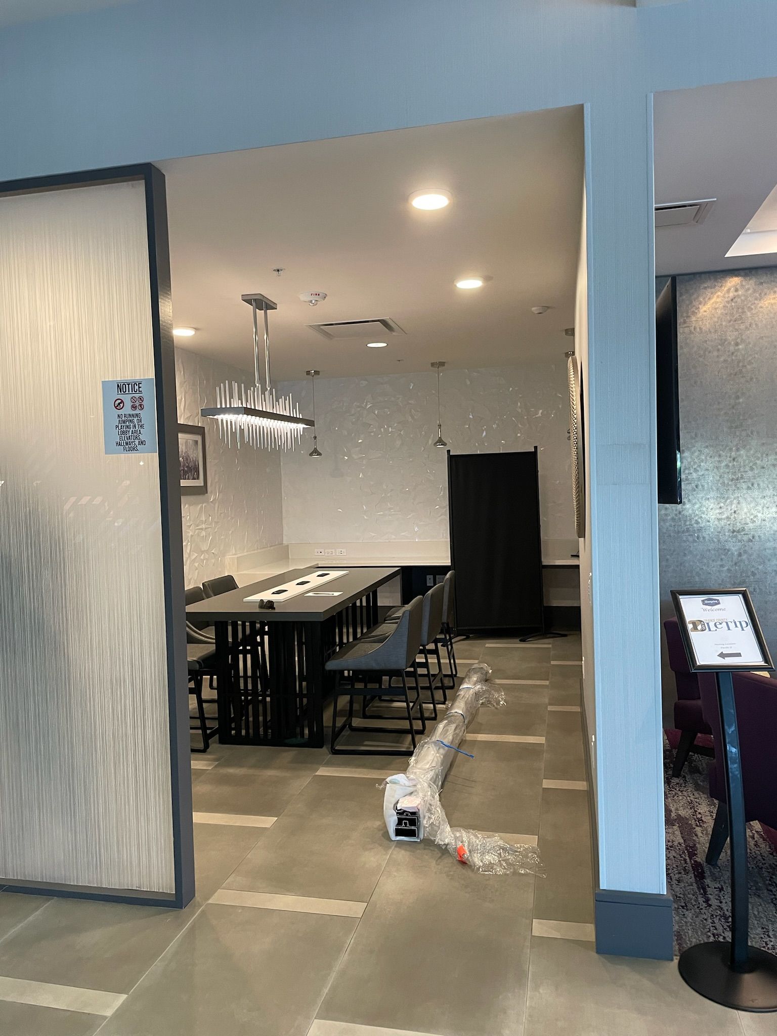 Long dining table in a room with textured wall, chandelier, and a decorative frosted door.