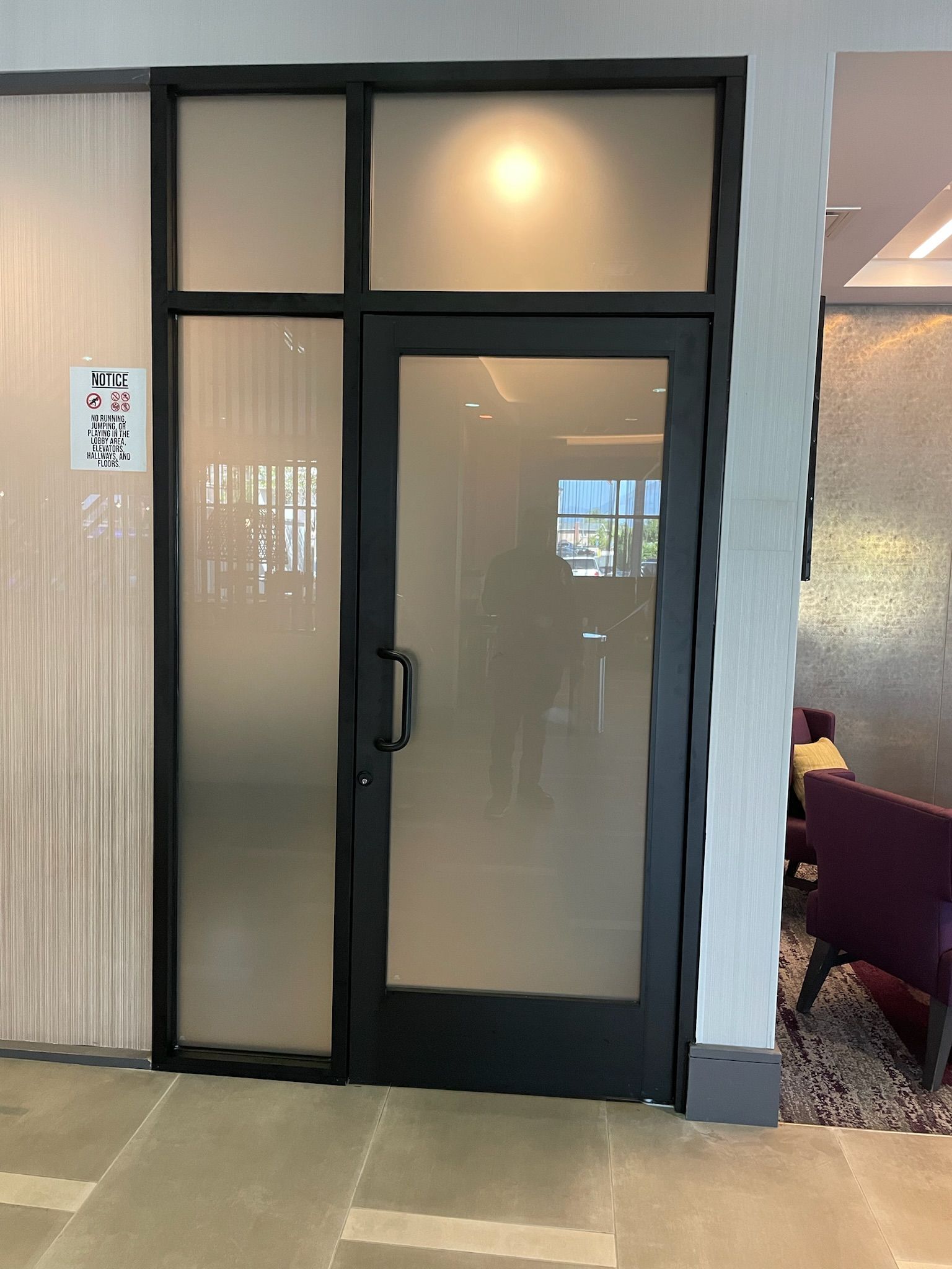 Black framed glass door with frosted side panel and top window, with a sign.