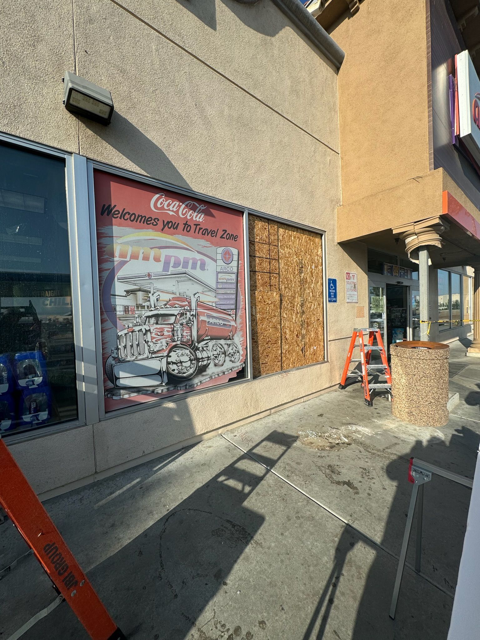 Exterior of a building with a boarded-up window, a ladder, and a partially open door.