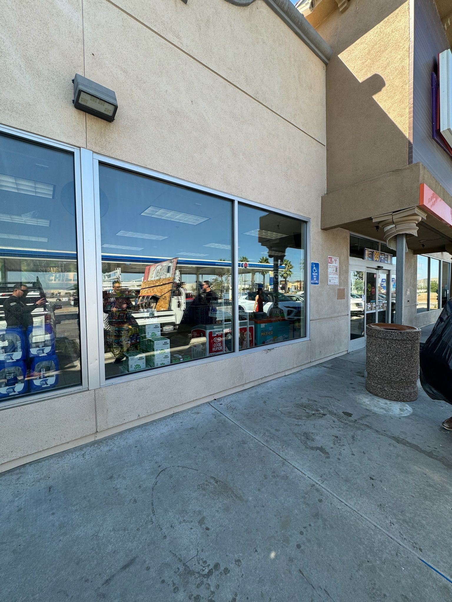 Exterior view of a store with large windows, sidewalk, and a concrete building.